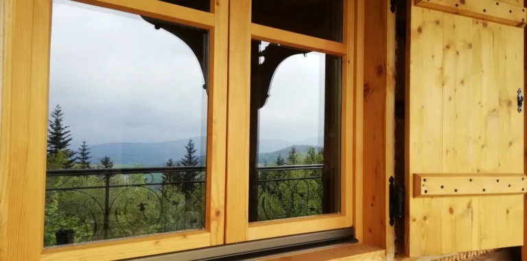 Widok na góry przez drewniane okno z okiennicą