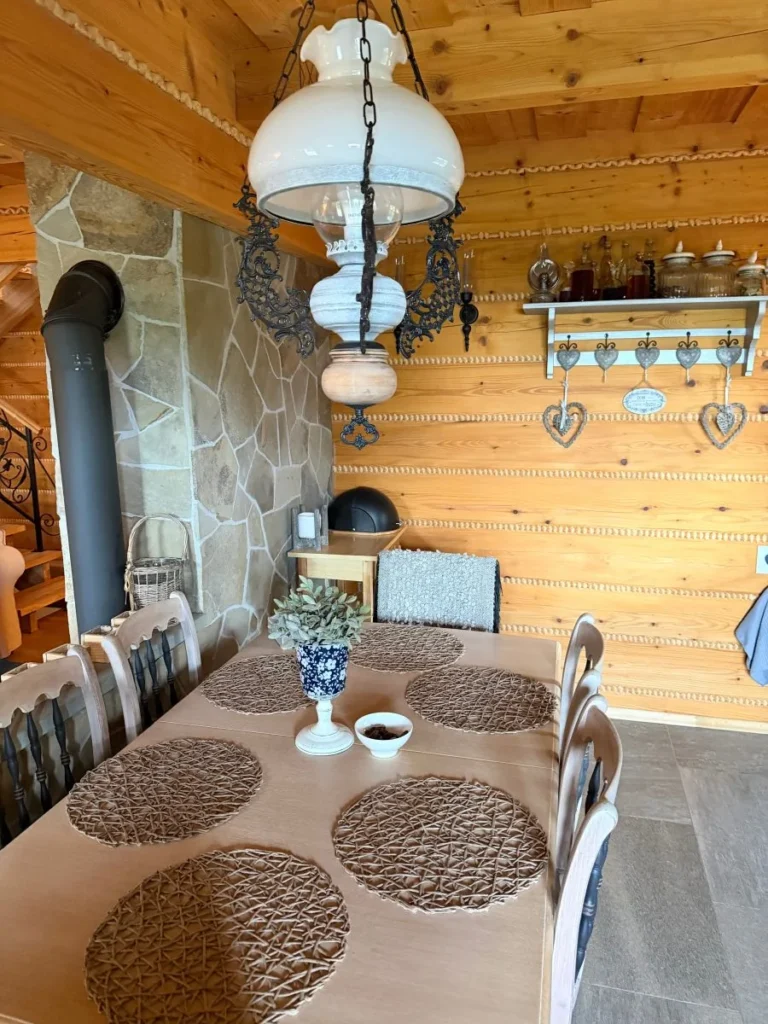 Stół w jadalni oraz piec na tle drewnianej ściany